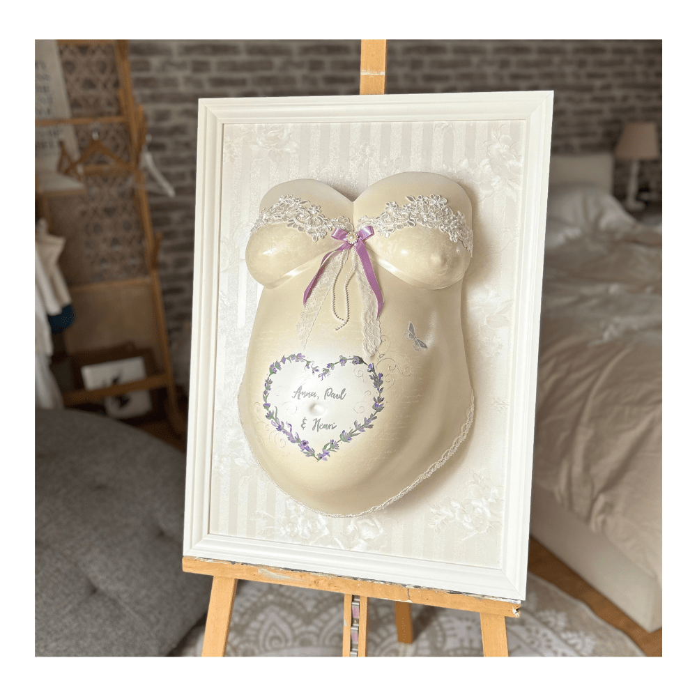 „Weißer 50x70 cm Bilderrahmen mit zarter weiß-cremefarbener Streifen- und Rosen-Tapete, Babybauch-Gipsabdruck cremefarben mit Lavendelblüten, mit den Namen und Geburtsdaten der drei Kinder, verziert mit Spitzenapplikationen am Busen – professioneller Veredelungsservice für Schwangerschaftsabdrück - Atelier Body - pArts
