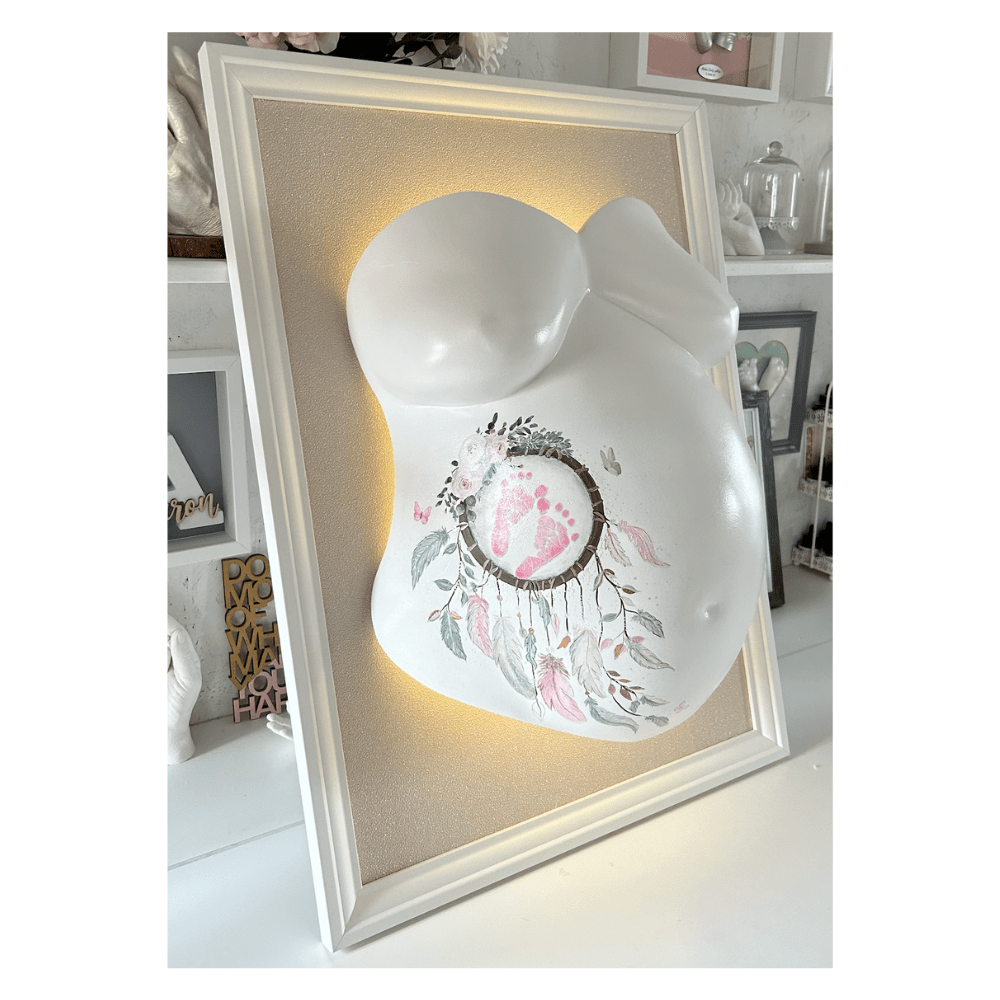 Bilderrahmen mit sandbeiger Tapete, elegant mit leichtem Glitzer, Babybauch-Gipsabdruck weiß lackiert mit Ornament, veredelt mit Glitzer, dekoriert mit Traumfänger in Rosa, Mint und Braun sowie Rosenschmetterling – professioneller Veredelungsservice für Schwangerschaftsabdrücke. - Atelier Body - pArts