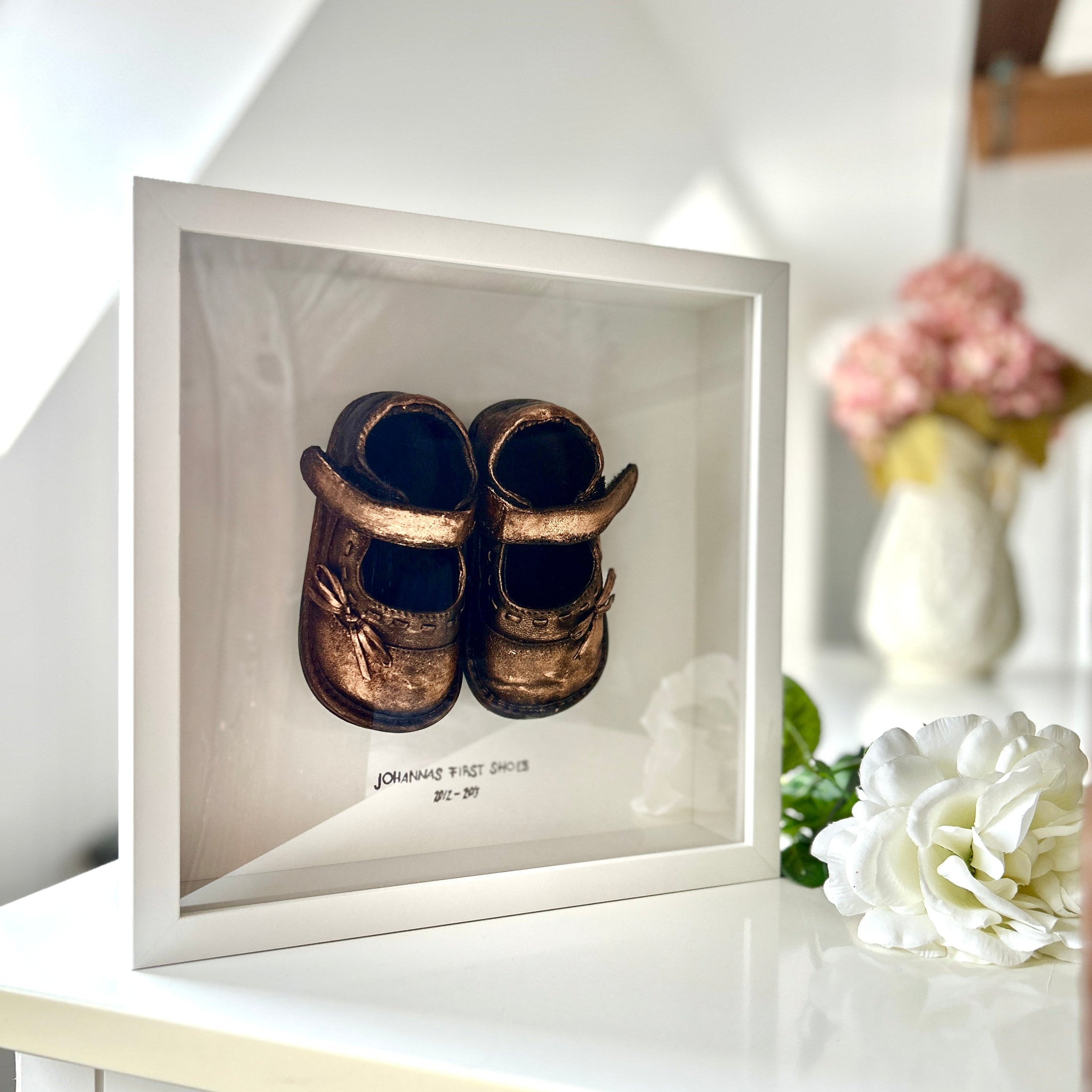 Babyrahmen mit den ersten Schuhen, veredelt in Gold – einzigartiges Unikat und liebevolle Erinnerung an die ersten Schritte.