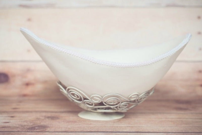 Das Bild zeigt eine elegante weiße Belly Bowl aus einem Babybauch Gipsabdruck mit feiner weißer Posamentenborte. Die handgefertigte Bauchschale wurde von beiden Seiten professionell verspachtelt, geschliffen und lackiert und dient als stilvolles Wohnaccessoire auf einer Kommode oder im Kinderzimmer. Die Belly Bowl kann dekorativ genutzt oder als besonderes Fotoaccessoire für Baby- und Newbornshootings eingesetzt werden und bewahrt die einzigartige Form des Schwangerschaftsbau - Atelier Body - pArts