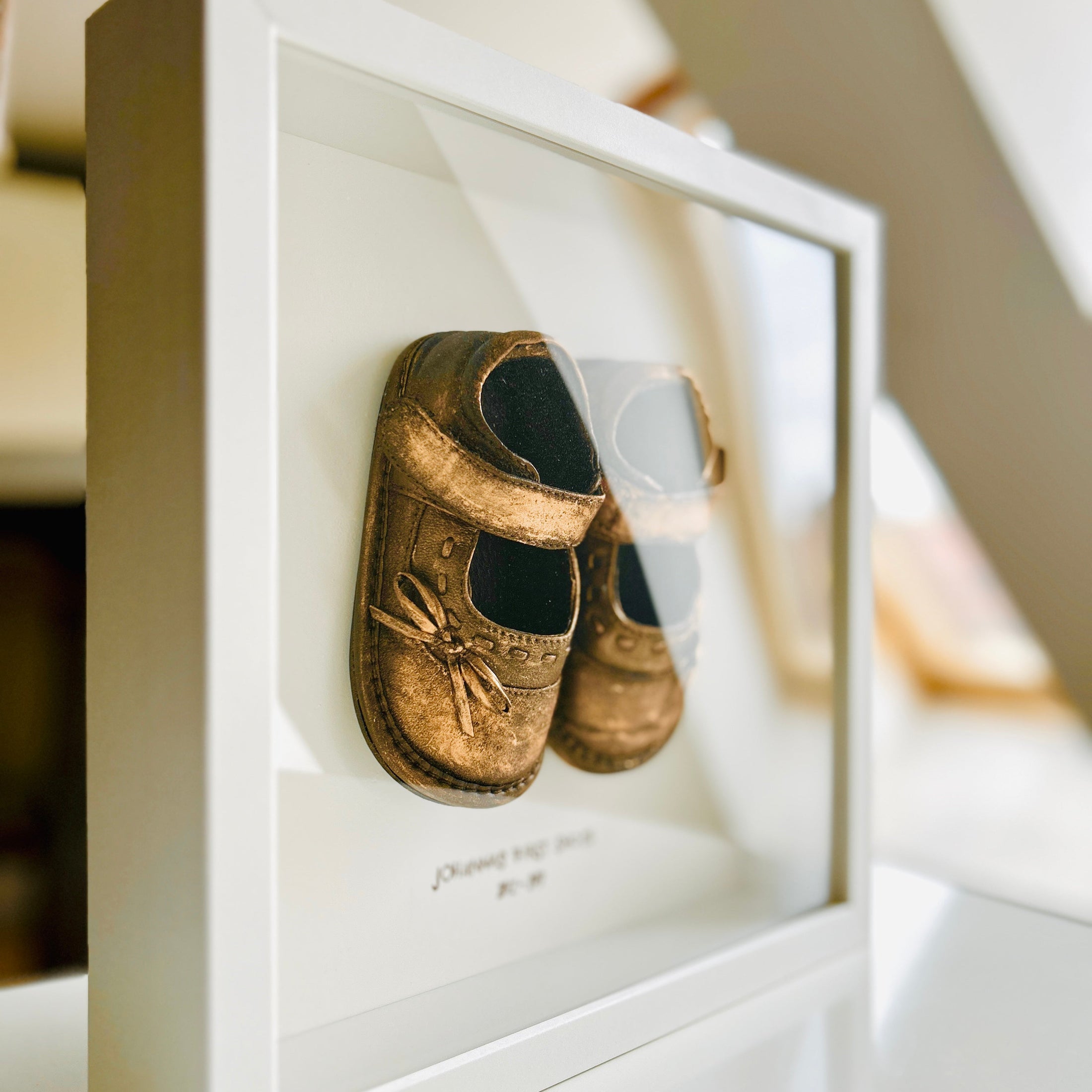 Erinnerungsrahmen mit silberfarbenen Babyschuhen, personalisierbar mit Name und Datum, gefertigt in Handarbeit.